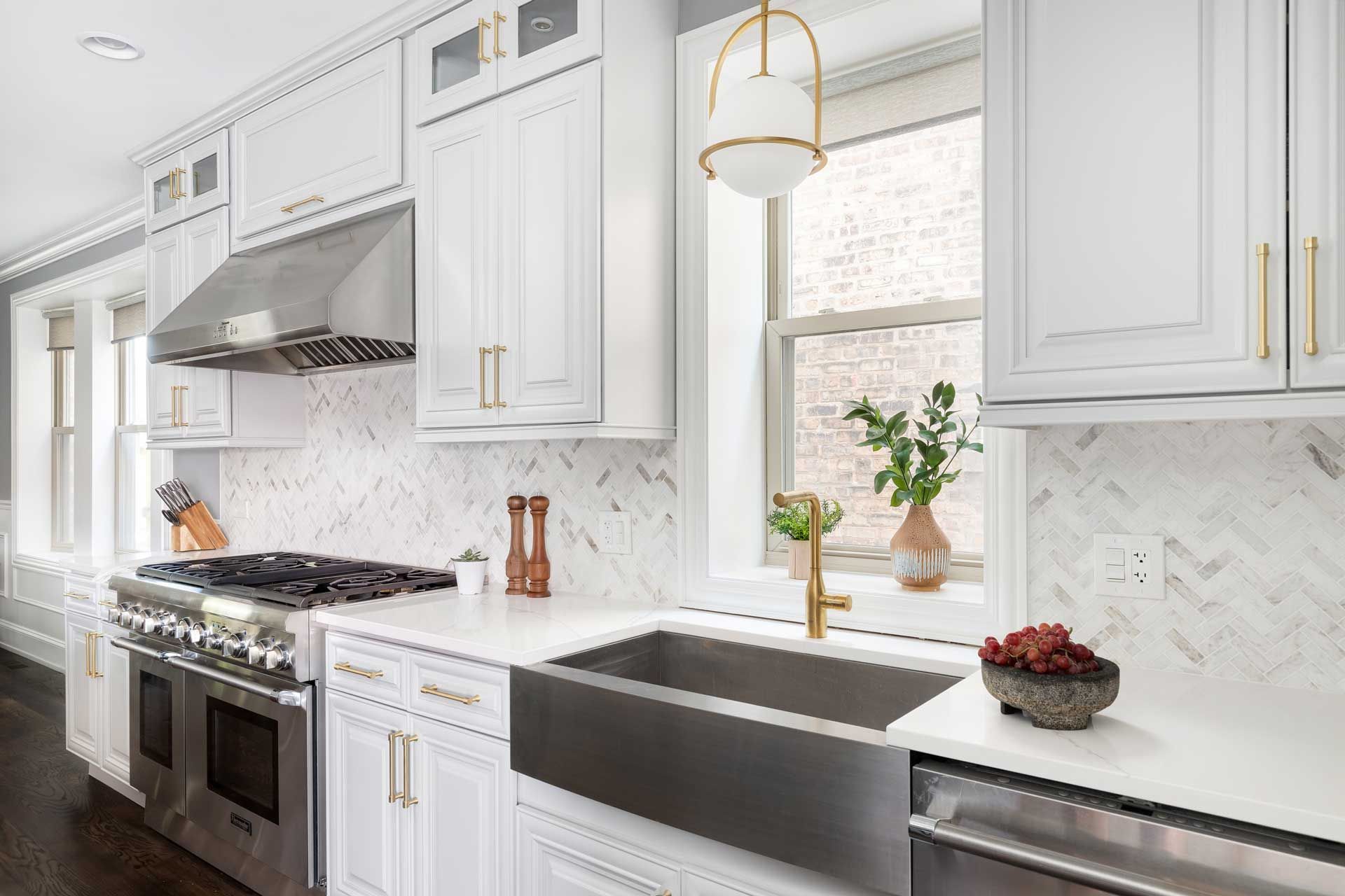 White kitchen with marble backsplash, stainless steel appliances, and gold accents.