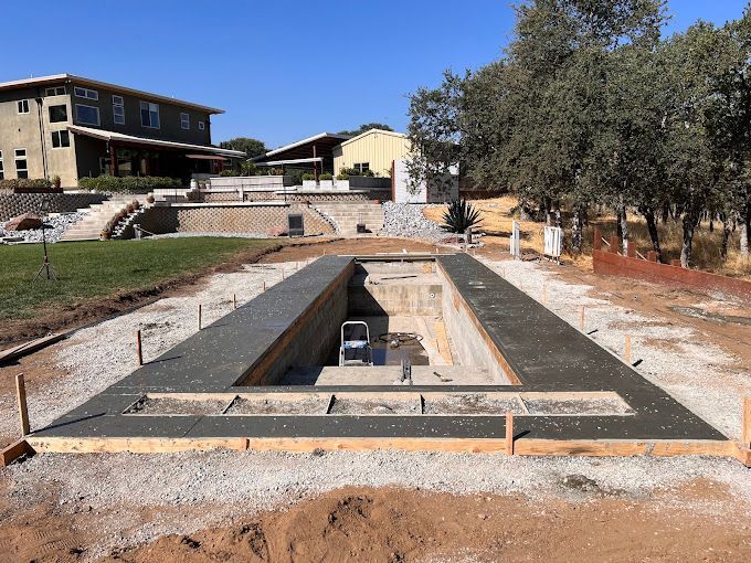 A large concrete pool is being built in a yard