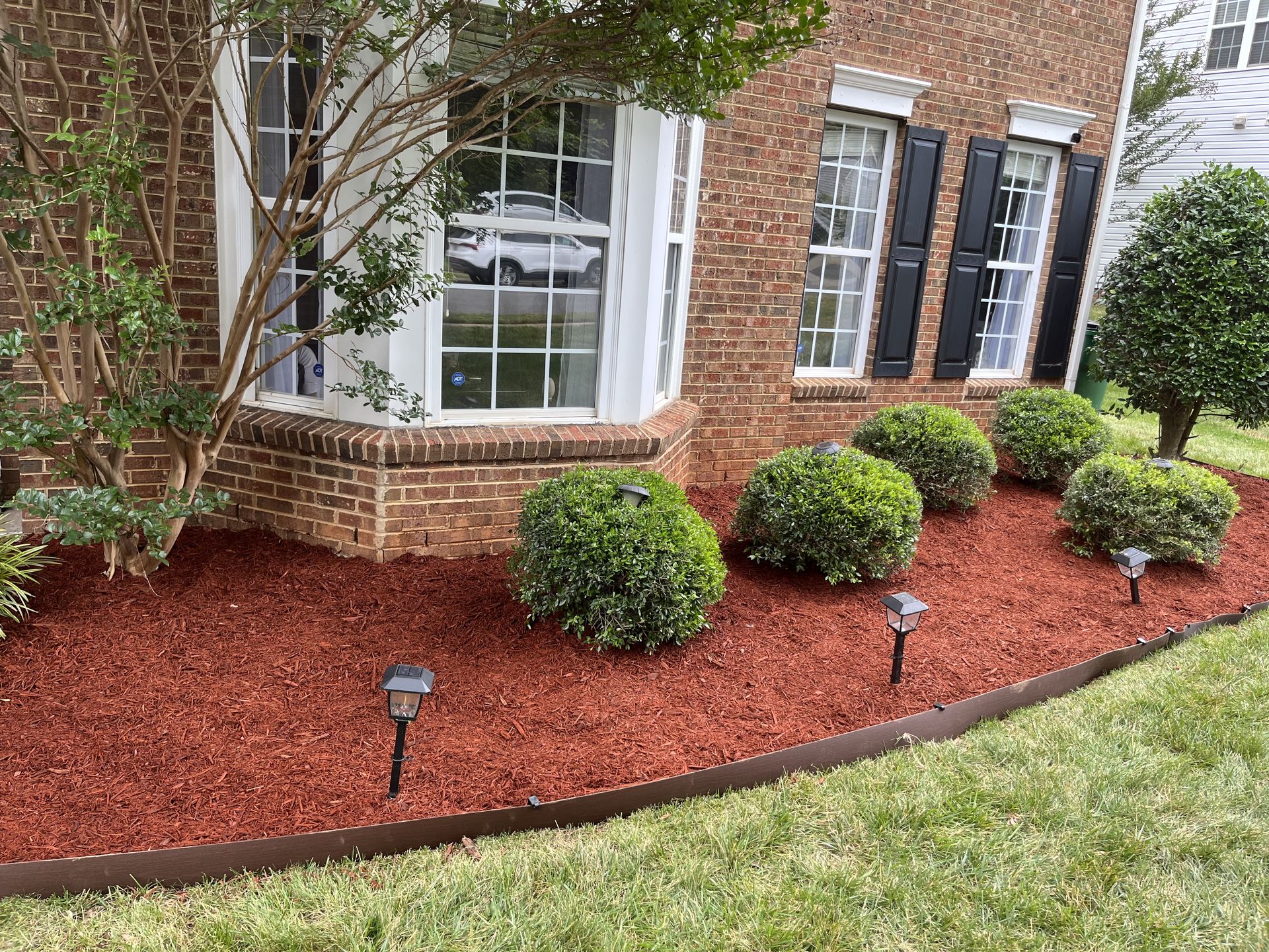 A brick house with a lush green lawn in front of it.