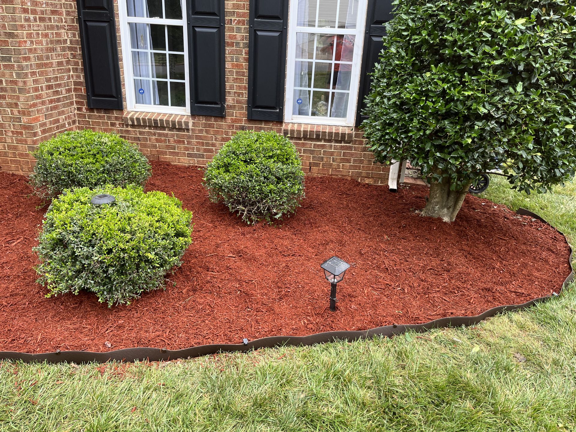 A brick house with a red mulch bed in front of it.