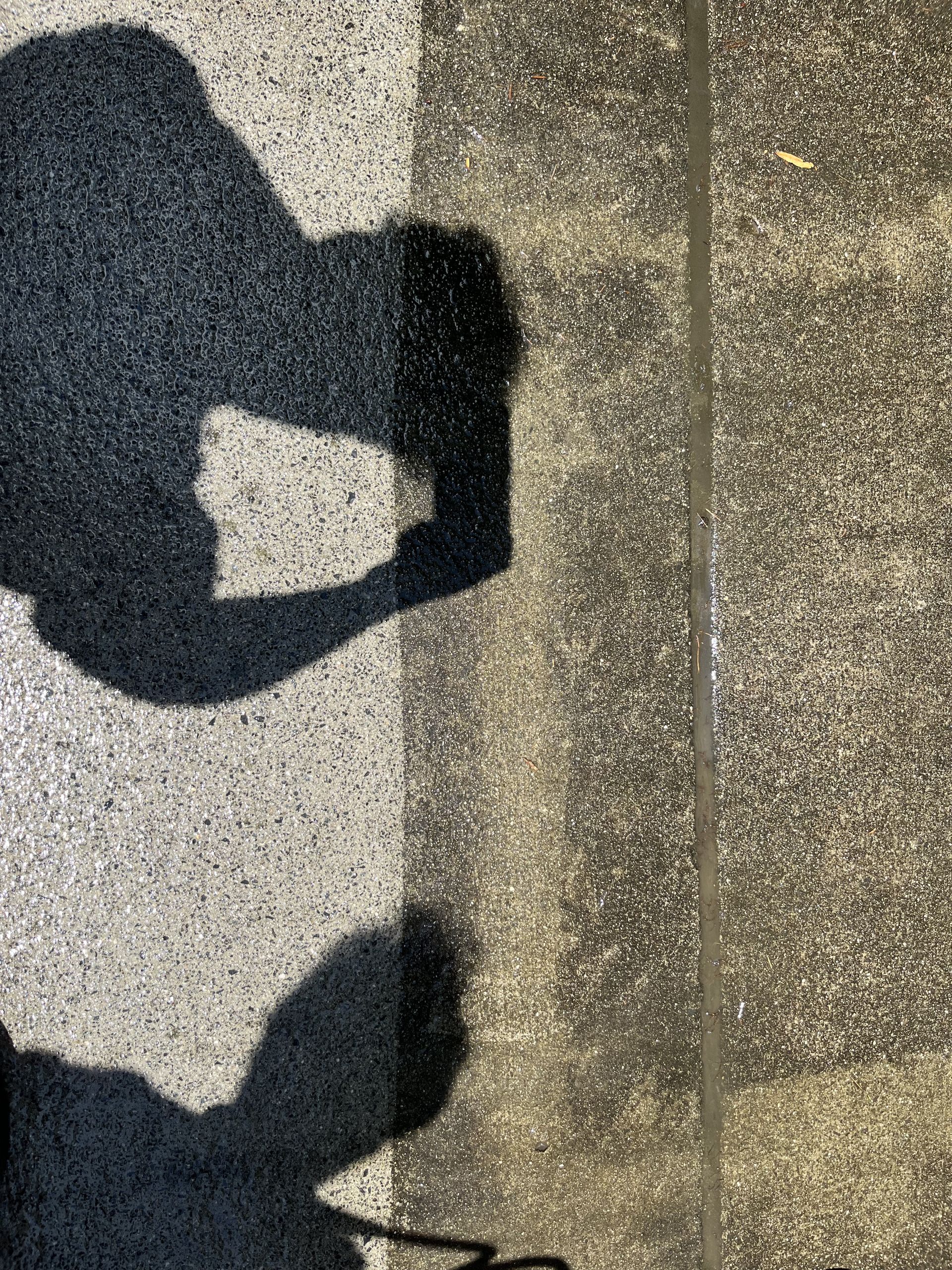 A shadow of a person standing on a concrete surface.