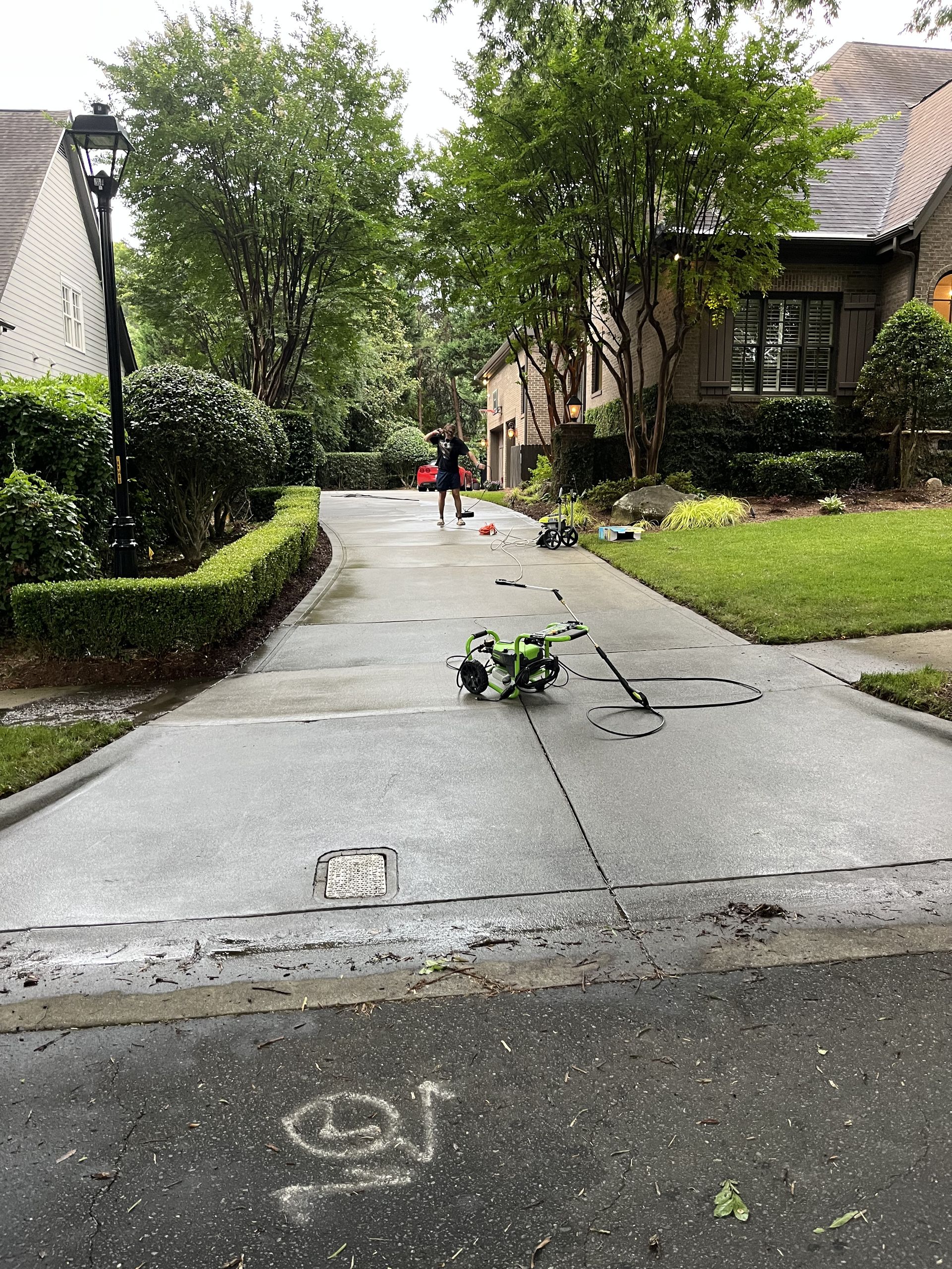 A drone is sitting on the side of a concrete driveway next to a house.