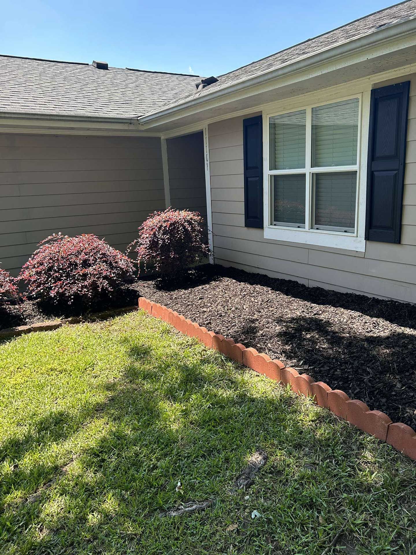 A house with a lot of plants in front of it.