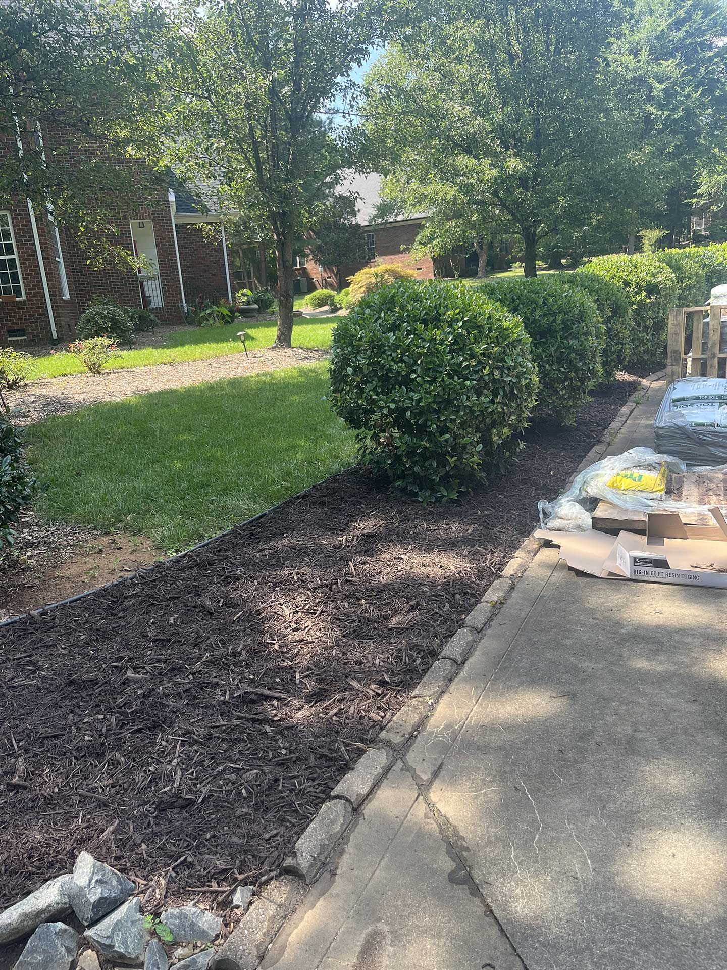 A sidewalk leading to a lush green yard with a house in the background.