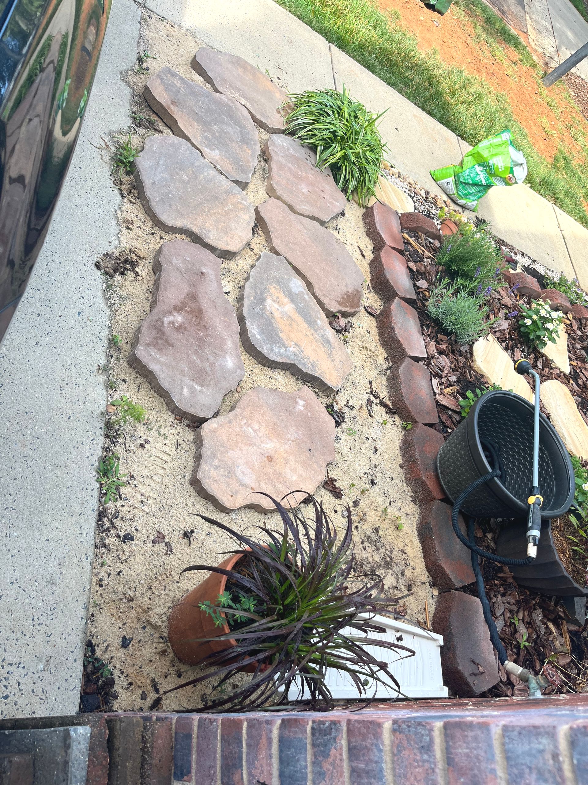 A brick house with a lush green lawn and bushes in front of it.
