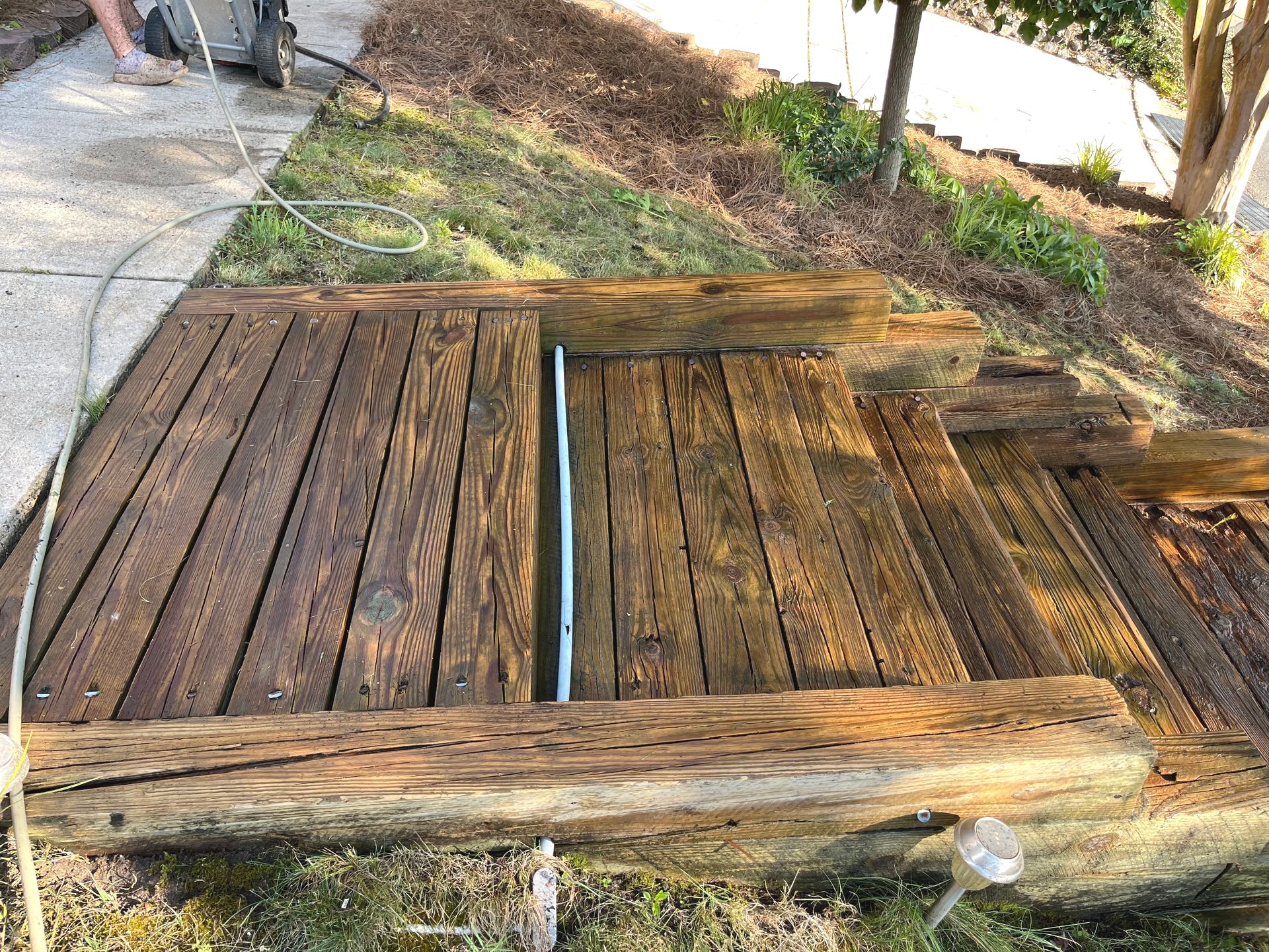 A man is cleaning a wooden deck with a pressure washer.