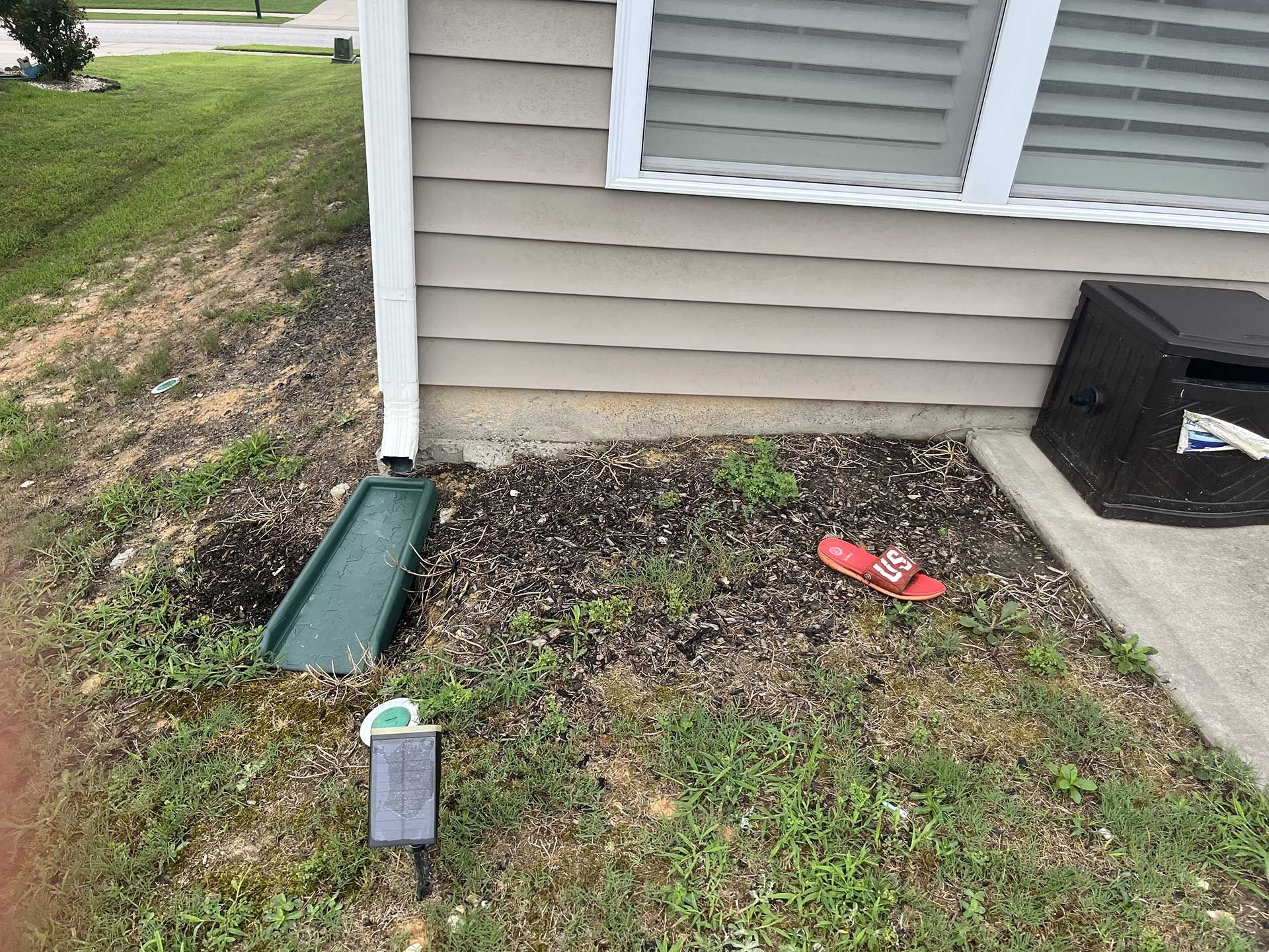 A house with a green slide in the grass in front of it.