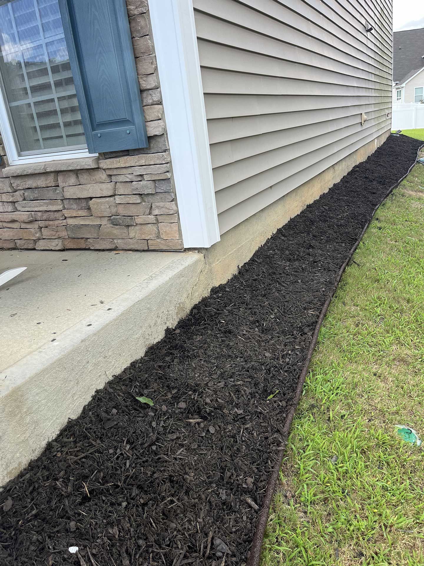 A house with a lot of black mulch on the side of it.