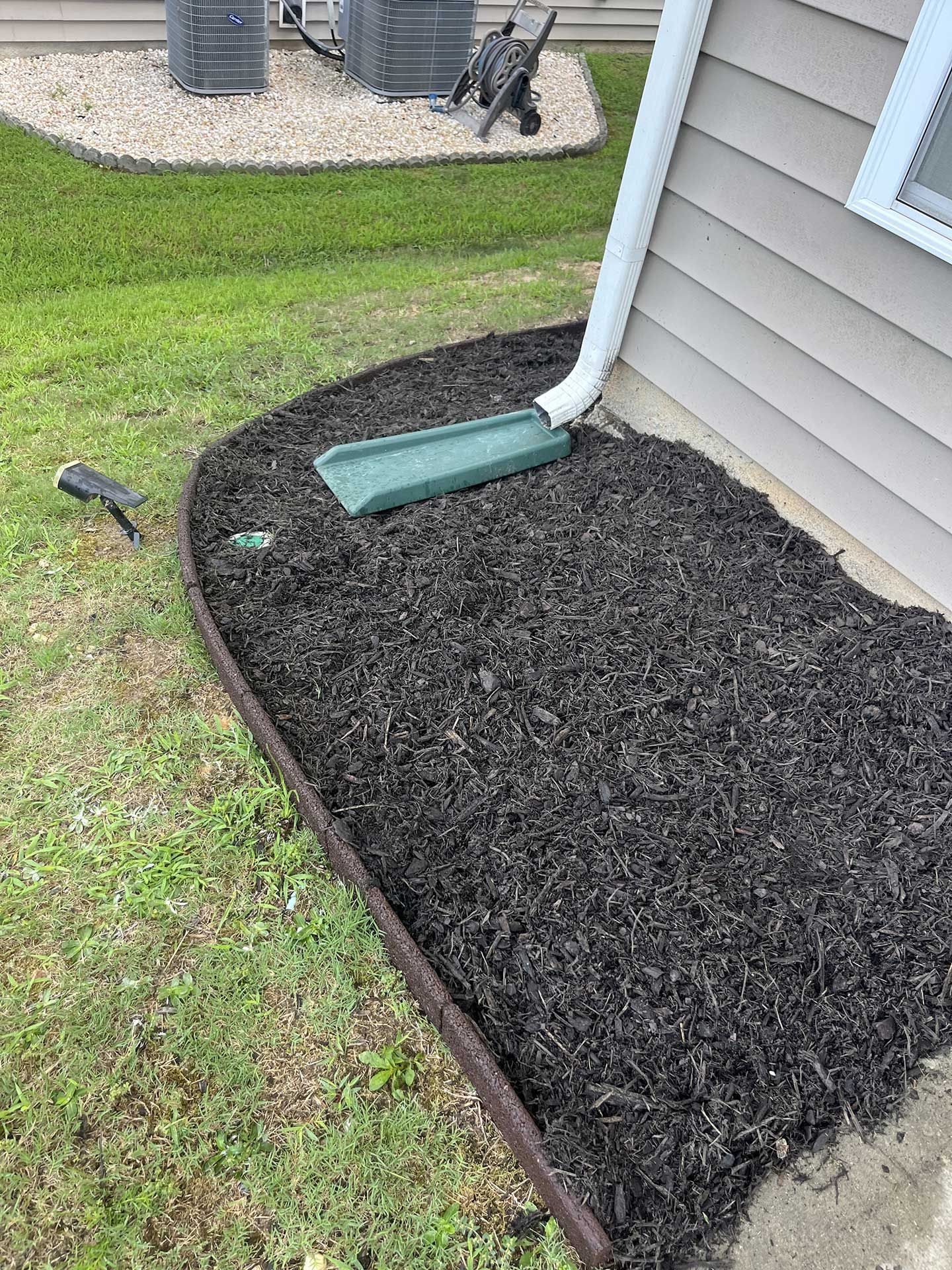 A hose is sitting on the ground next to a house.