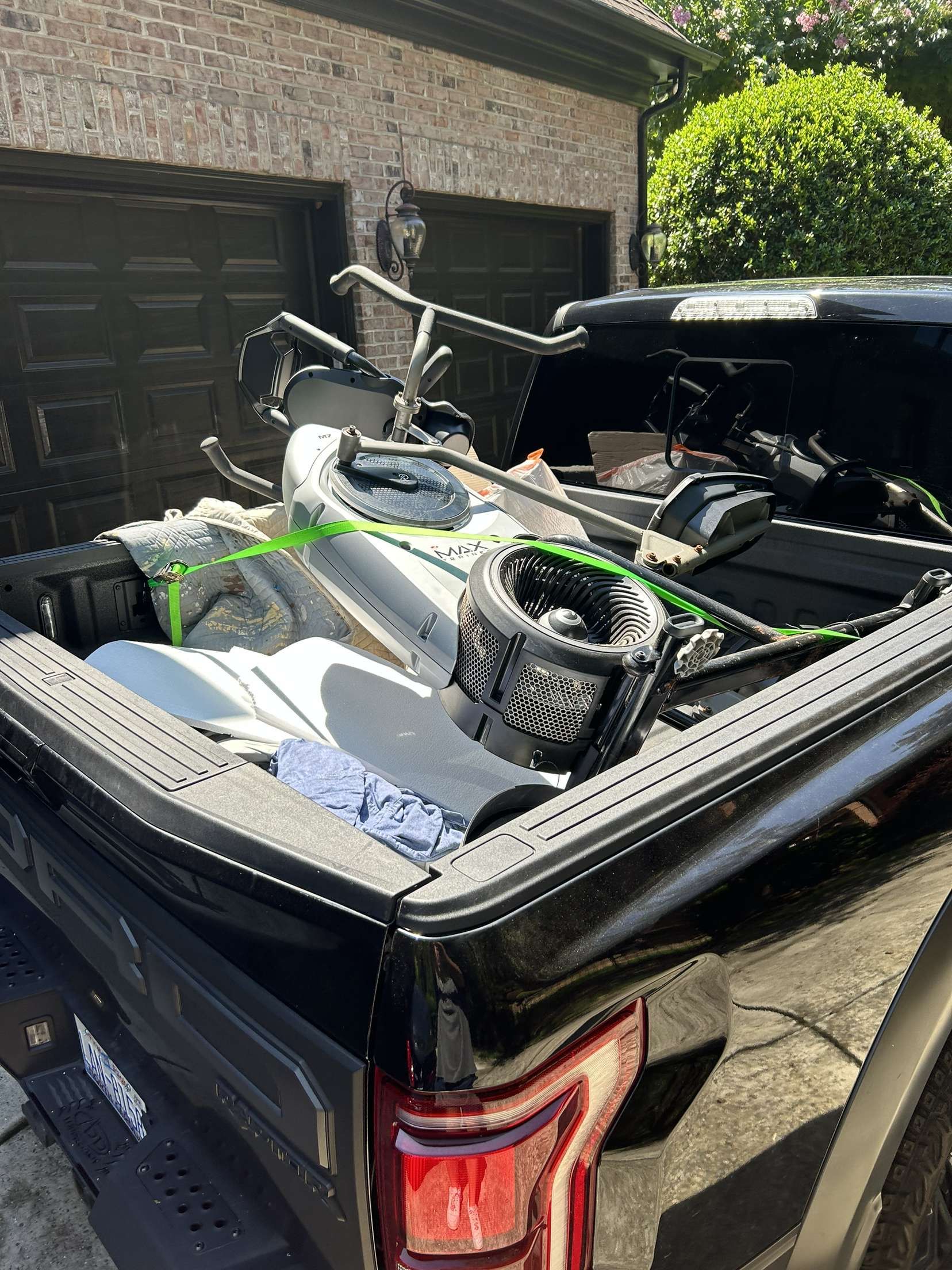Two men are standing in front of a car in a garage.