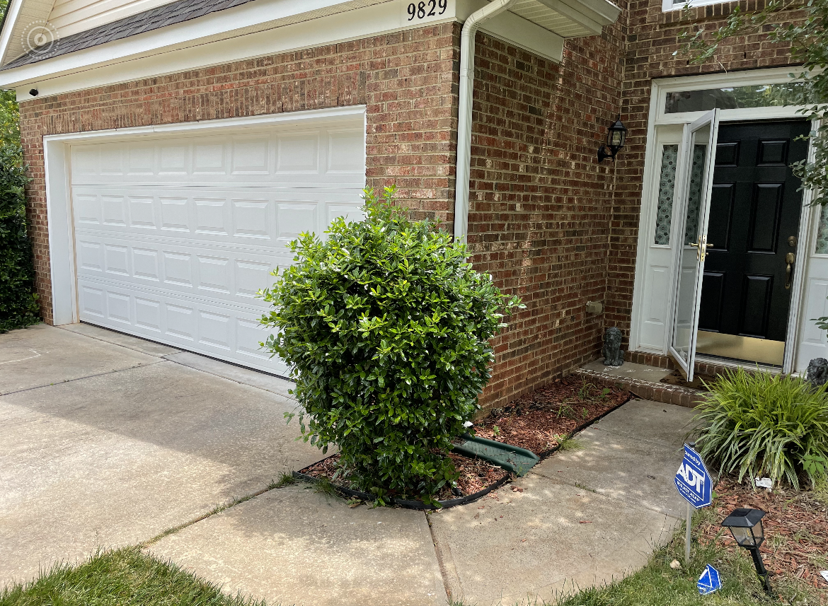 A picture of a brick house with a white garage door.