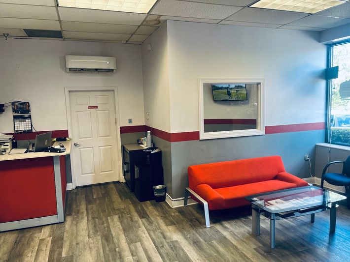 A waiting room with a red couch and a table.