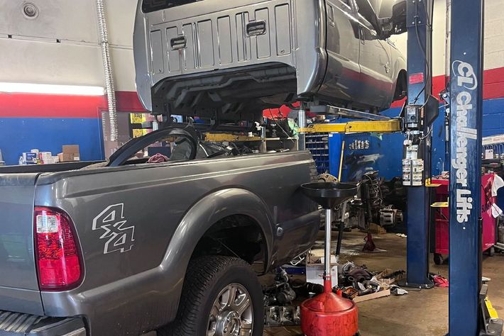 A truck is sitting on a lift in a garage.