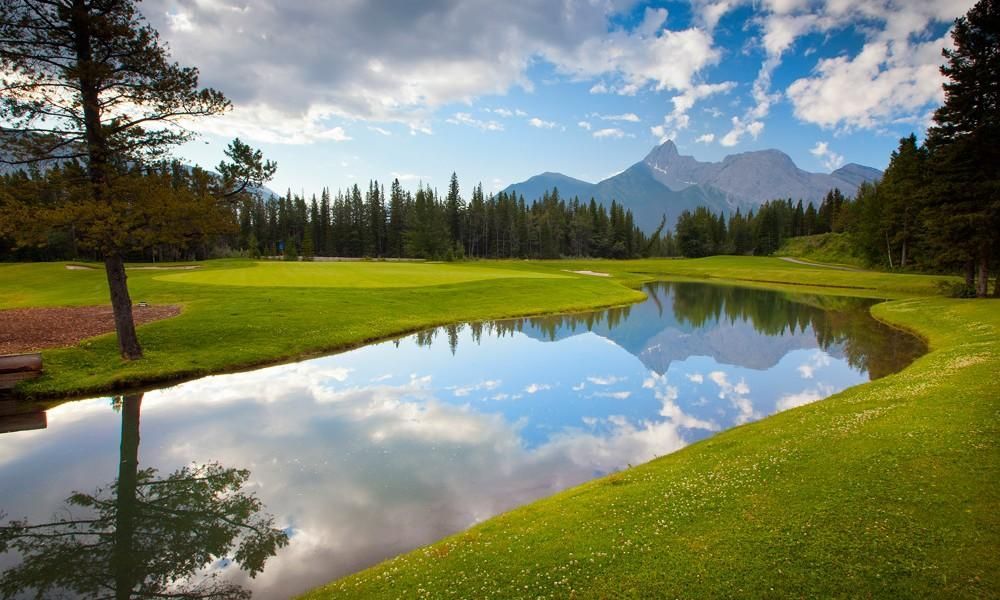 A river running through a golf course with mountains in the background