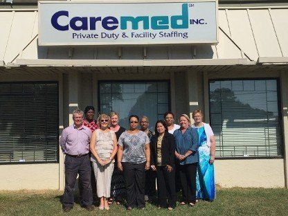 Caremed staff standing outside a medical office building under the Caremed sign