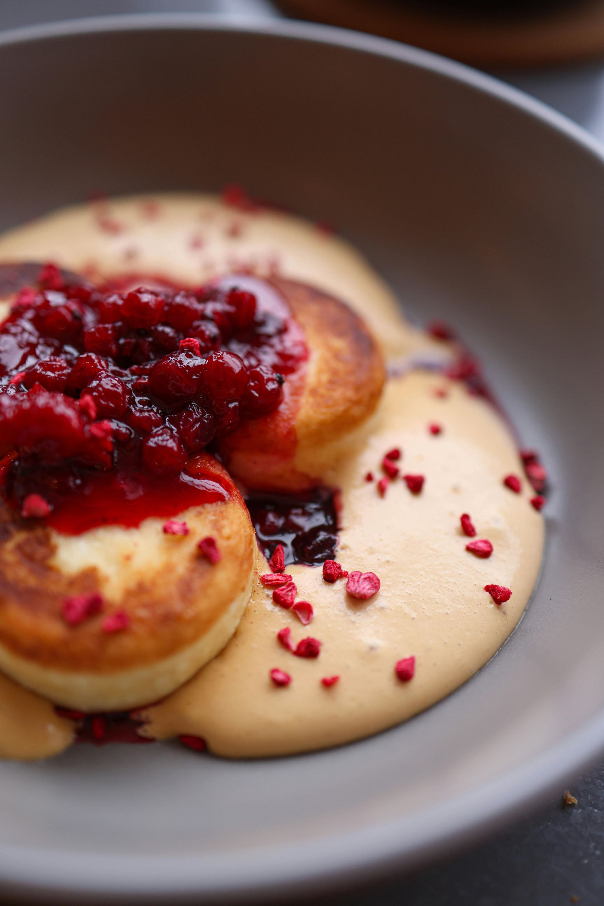 Pancakes topped with berry compote and creamy sauce in a bowl