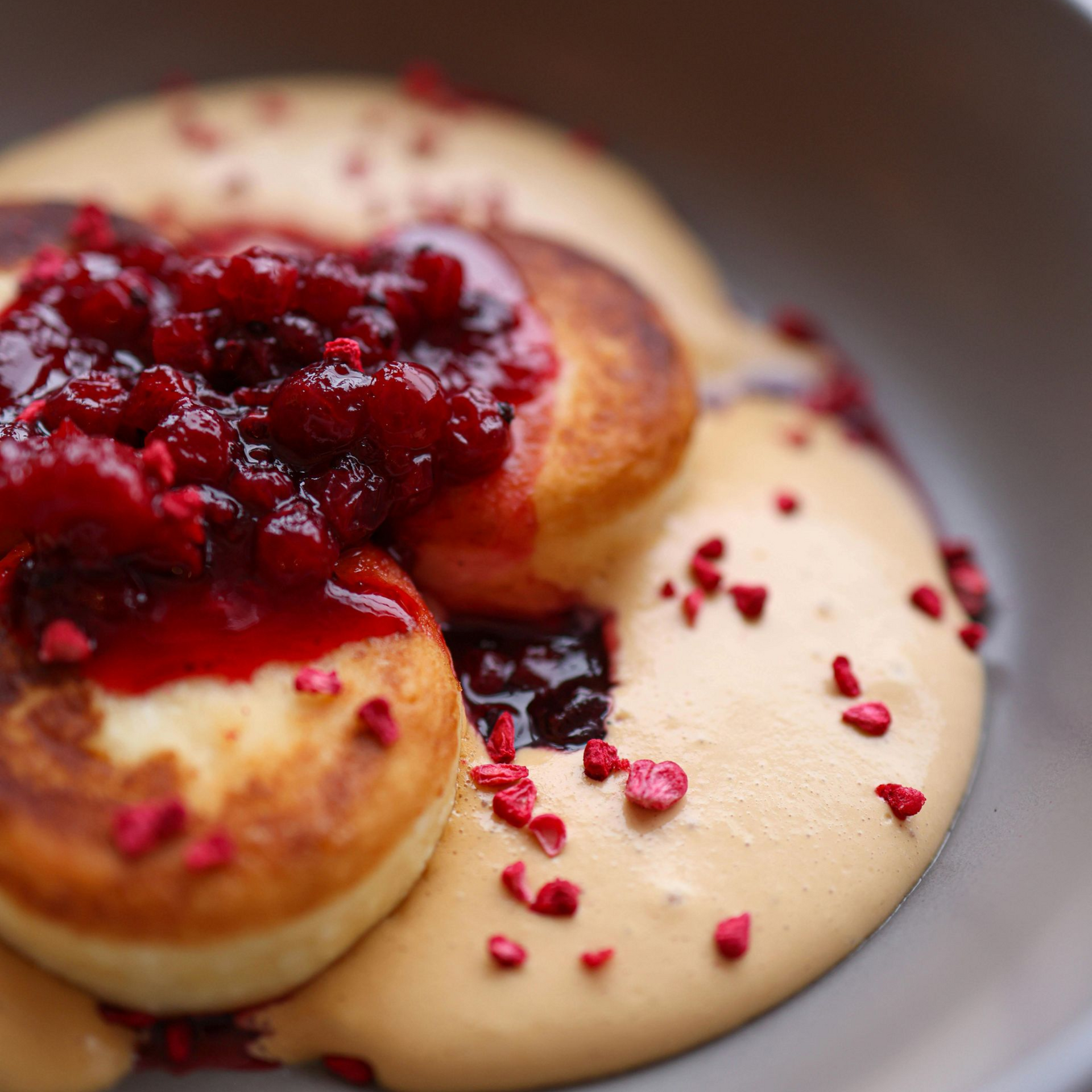 Pastries topped with red berry compote and drizzled cream on a plate