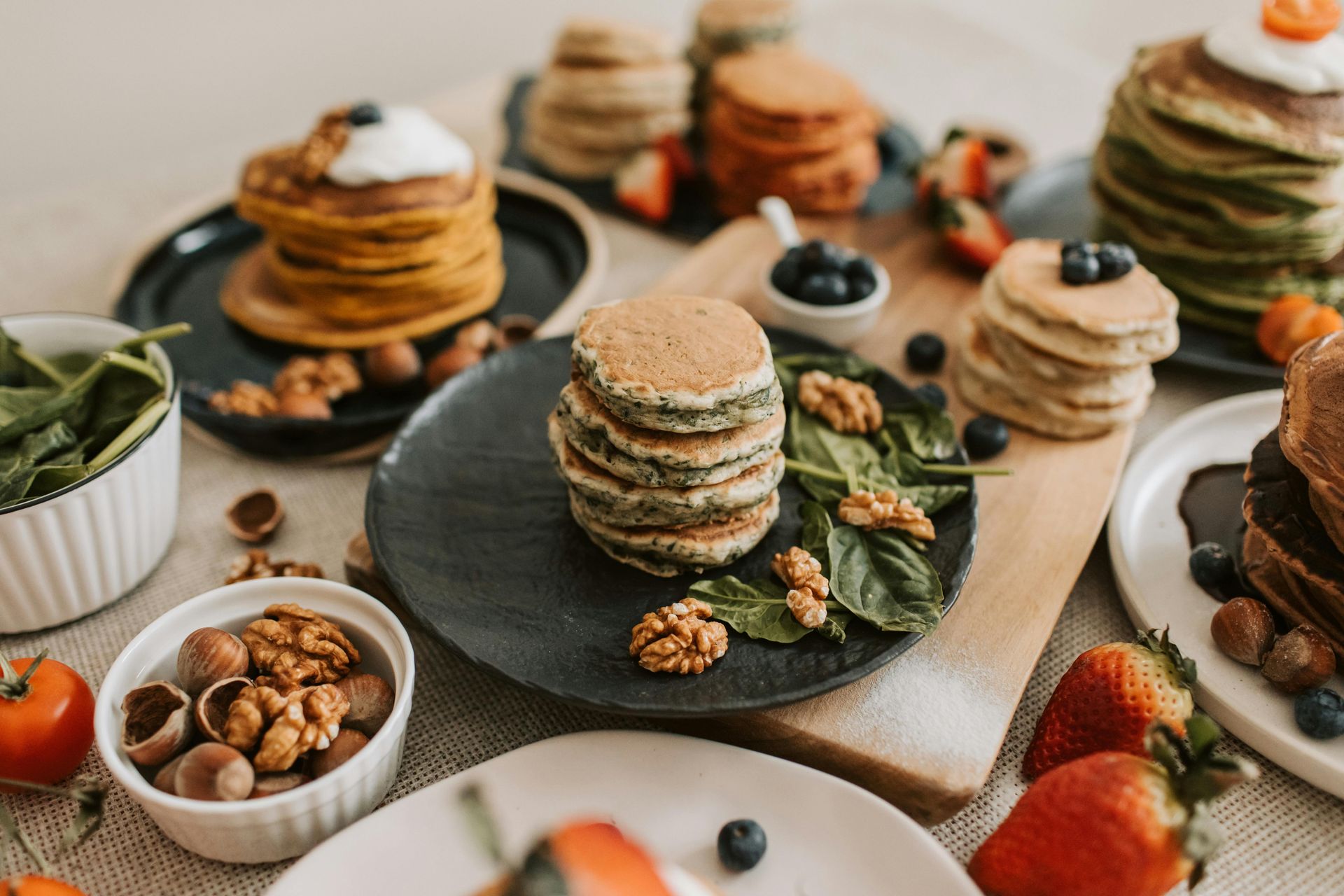 Assorted pancakes and fruit on plates and trays at a breakfast spread
