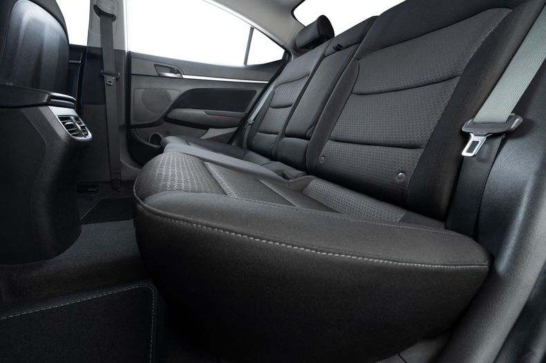 Rear car seat interior with black upholstery and a folded center armrest