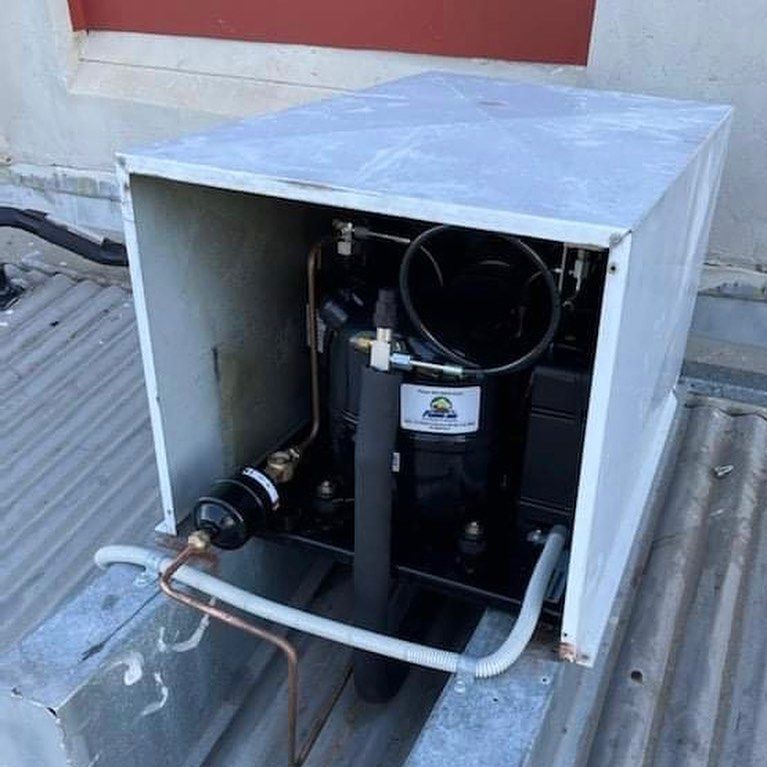 A Compressor Is Sitting Inside Of A White Box On A Roof — Frigid-Air PTY Ltd In Bangalow, NSW