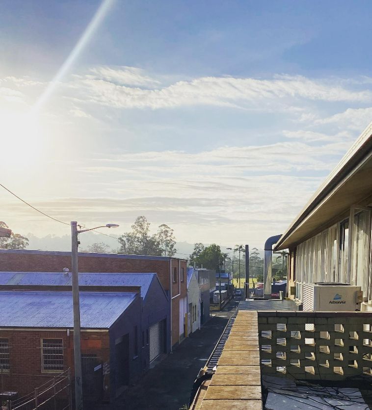 A Balcony Overlooking A Row Of Buildings With The Sun Shining Through The Clouds — Frigid-Air PTY Ltd In Bangalow, NSW