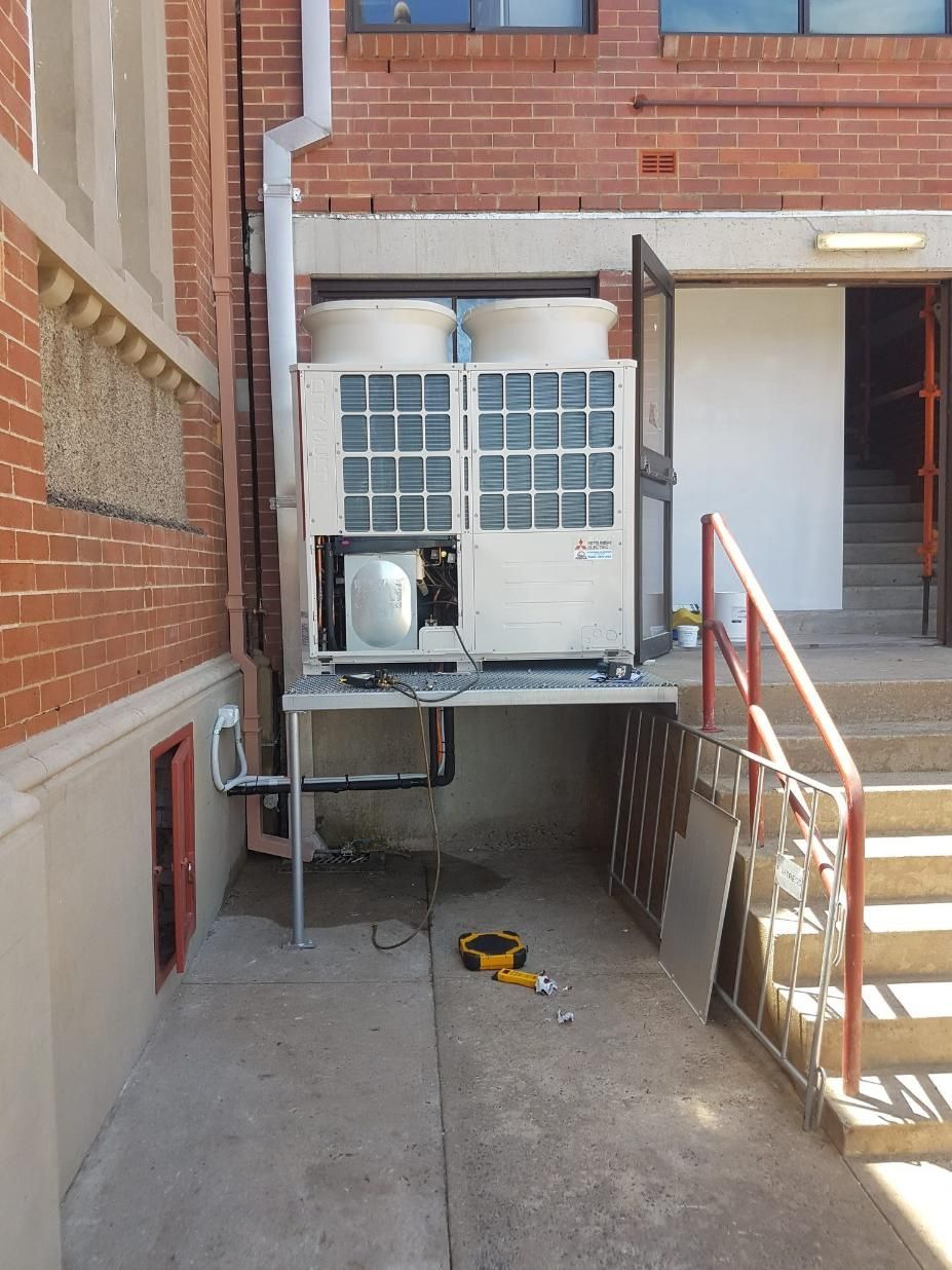 A Large Air Conditioner Is Sitting On The Side Of A Building Next To Stairs — Frigid-Air PTY Ltd In South Lismore, NSW