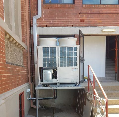 A Brick Building With An Air Conditioner On The Side Of It — Frigid-Air PTY Ltd In Lennox Head, NSW