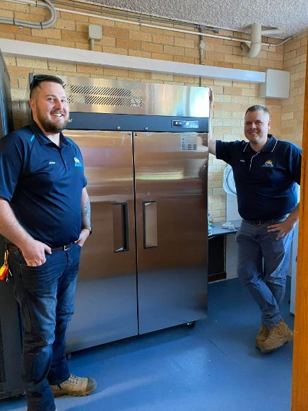 Two Men Are Standing Next To Each Other In Front Of A Refrigerator — Frigid-Air PTY Ltd In Lismore, NSW
