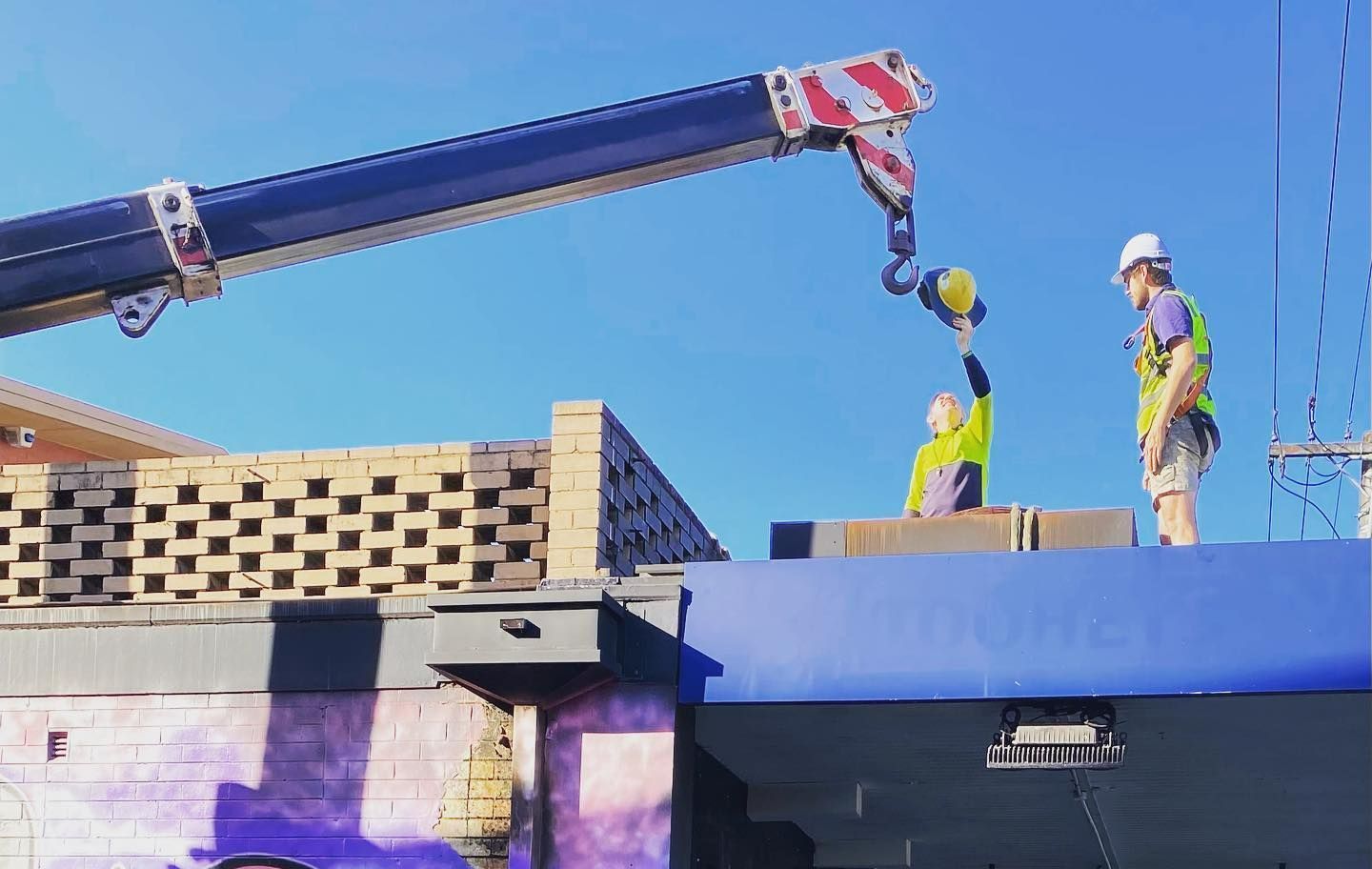 A Group Of Construction Workers Are Working On A Roof With A Crane — Frigid-Air PTY Ltd In Casino, NSW