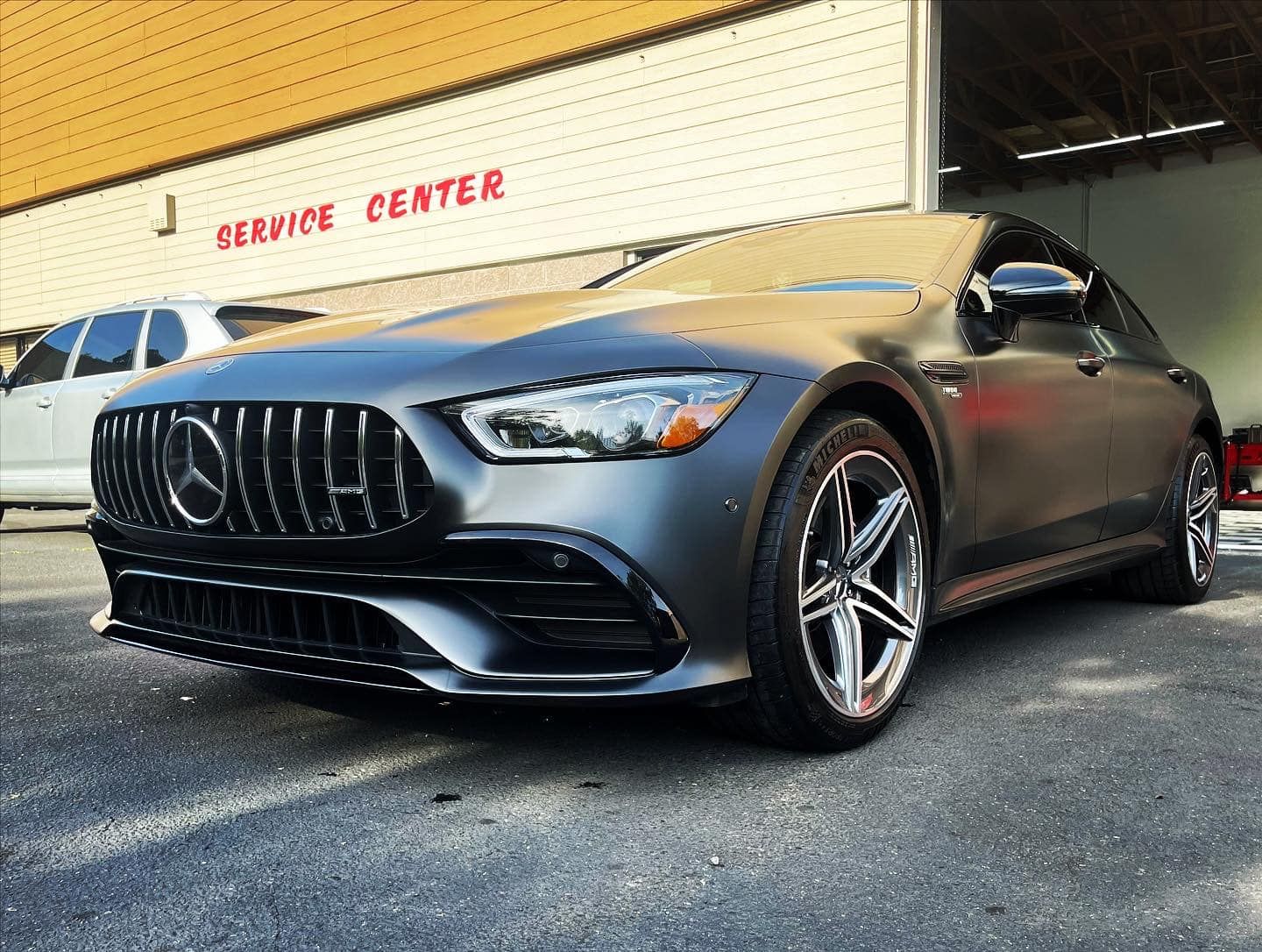 A mercedes benz gt63 amg is parked in front of a service center.