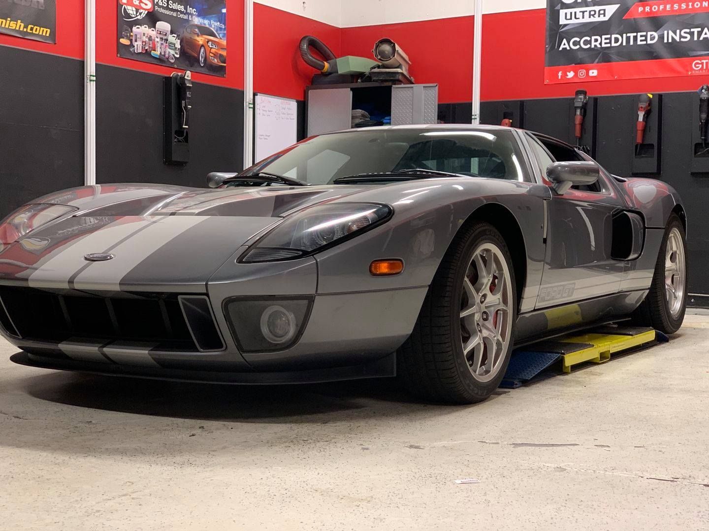 A gray sports car is parked on a lift in a garage.