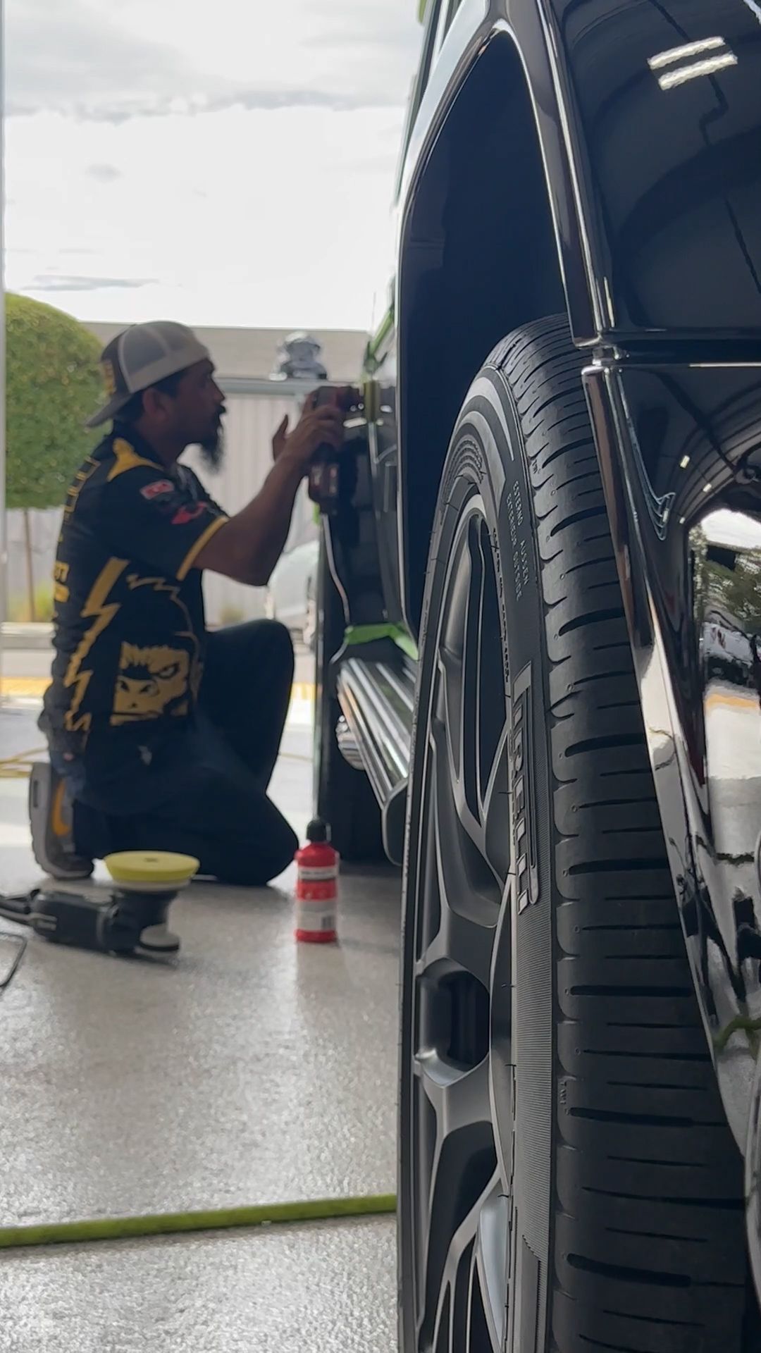A man is kneeling down polishing the side of a car.