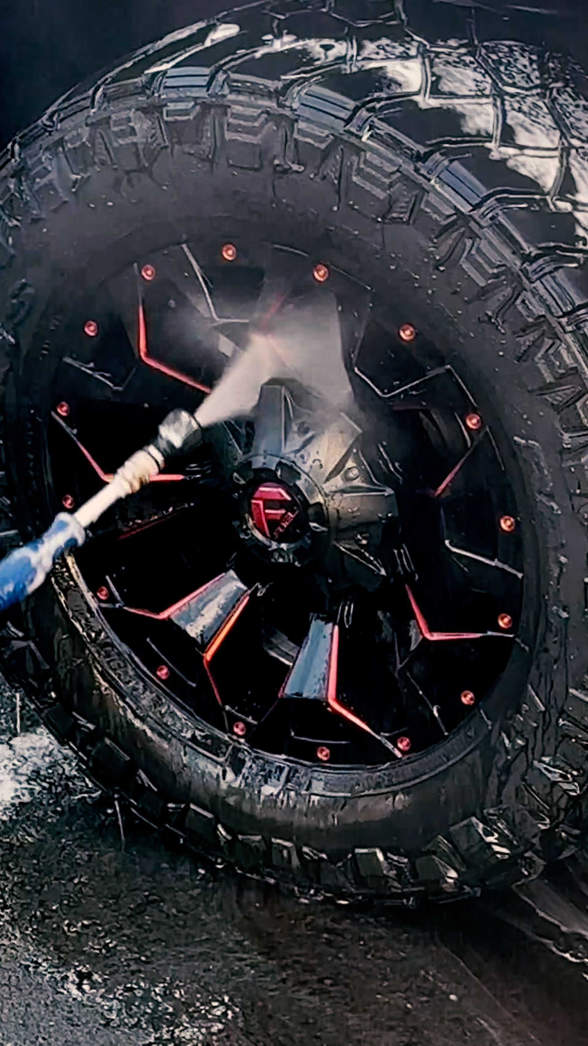 A person is cleaning a tire with a hose.