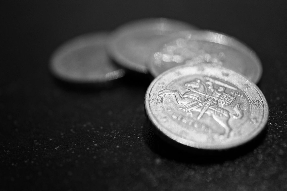 Three silver coins are stacked on top of each other on a black surface.