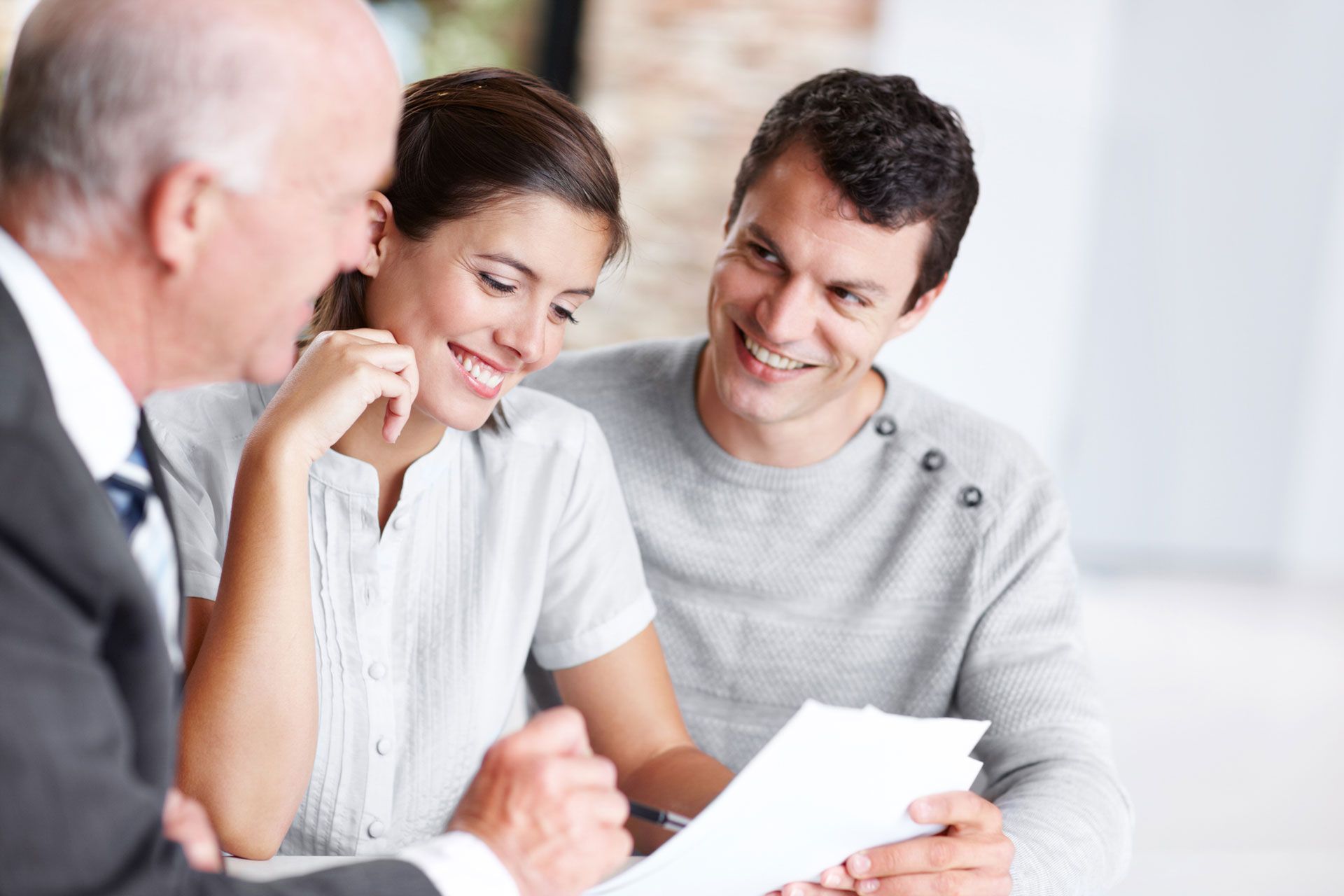 A man and a woman are sitting at a table looking at a piece of paper. A man and a woman are sitting at a table looking at a piece of paper.