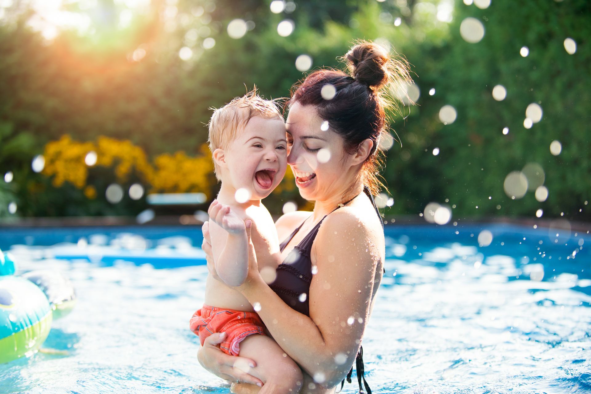 A woman is holding a baby in a swimming pool. A woman is holding a baby in a swimming pool.