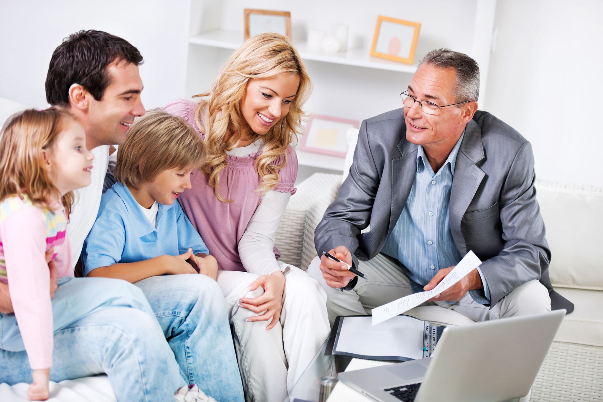 A family is sitting on a couch looking at a laptop. A family is sitting on a couch looking at a laptop.