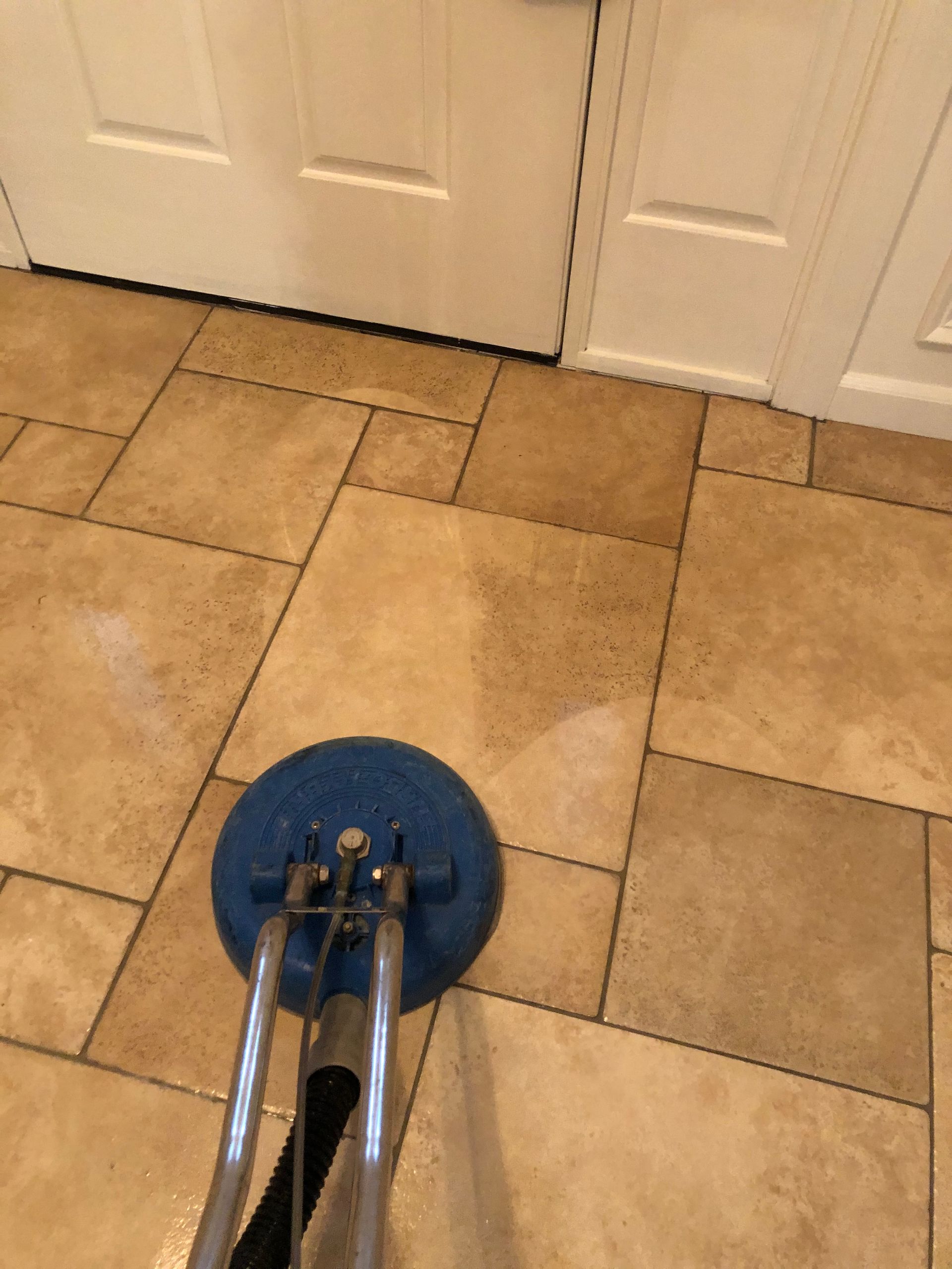 A tile floor is being cleaned with a vacuum cleaner.