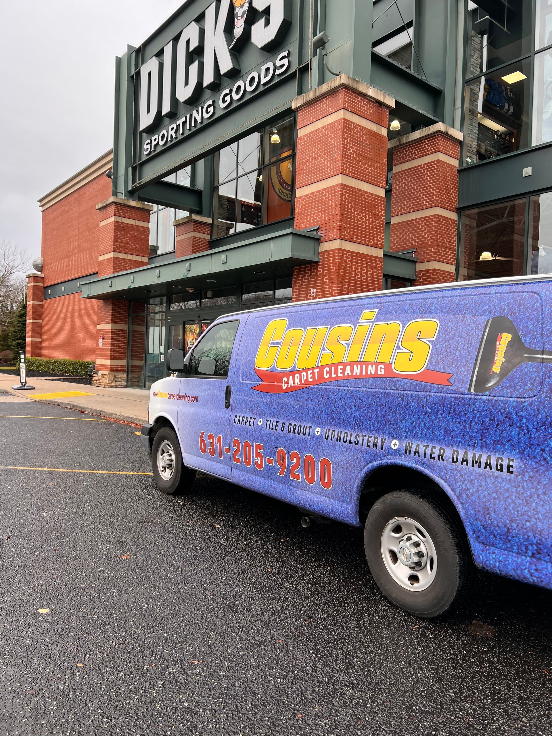 A blue van is parked in front of a brick building.