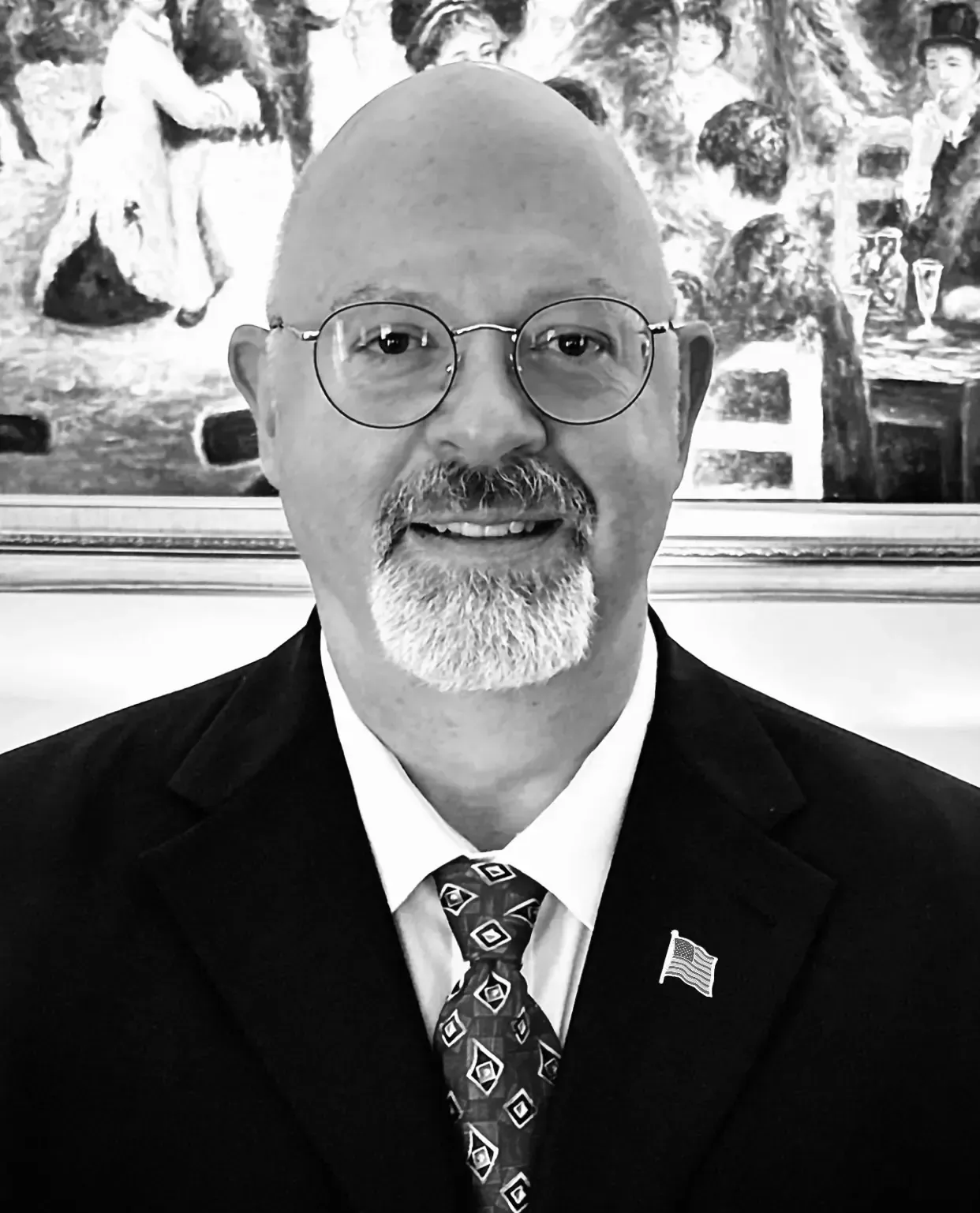 A man in a suit and tie is smiling in front of a painting.