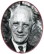 A black and white photo of a man wearing glasses and a suit and tie.