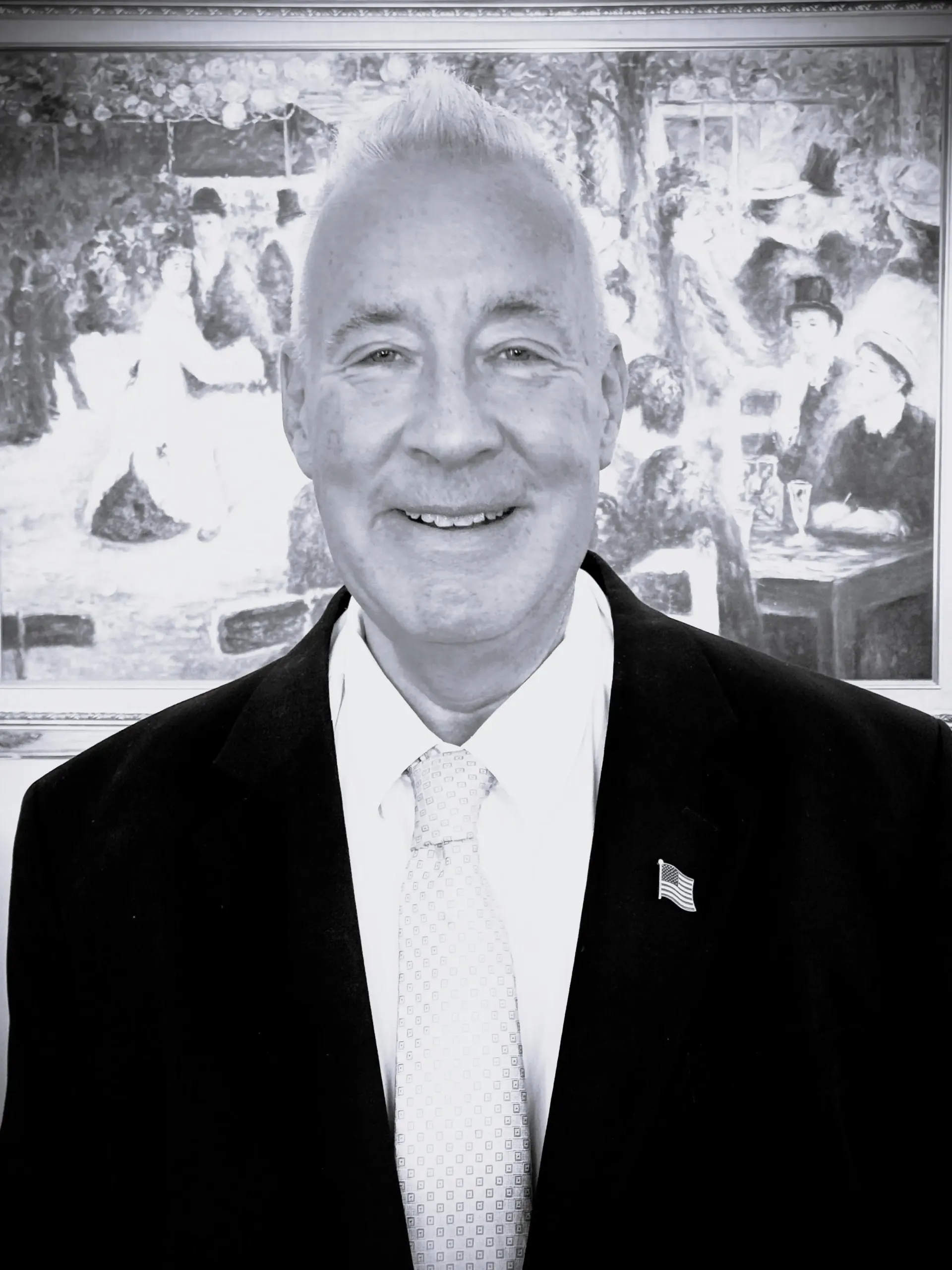 A man in a suit and tie is smiling in front of a painting.