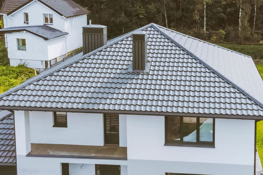 White House With a Gray Tiled Roof and Chimney, Nestled Among Trees — Callaway Roofing & Construction in Cobar, NSW