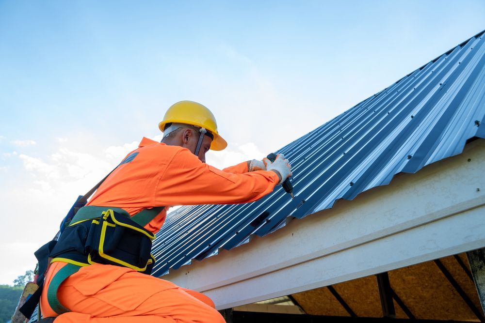 Roofer In Orange Jumpsuit And Hard Hat Installs Corrugated Metal Roofing, Against A Blue Sky — Callaway Roofing & Construction in Dubbo, NSW