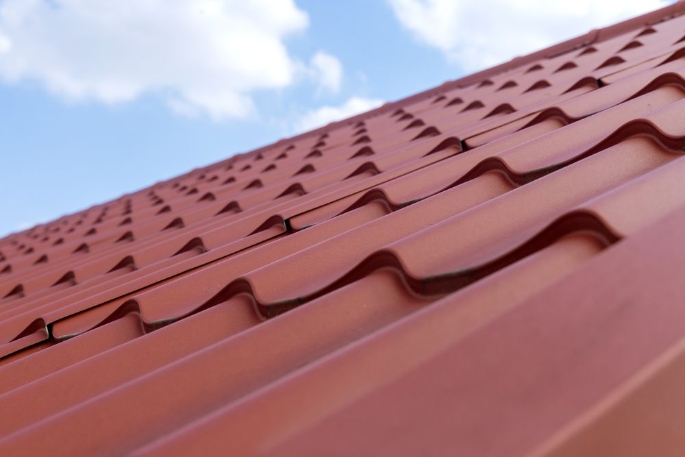 Red Metal Roof With a Wavy Pattern Against a Blue Sky — Callaway Roofing & Construction in Parkes, NSW