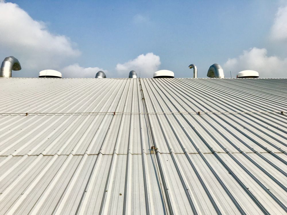 Metal Roof With Vent Pipes Against a Blue Sky With Clouds — Callaway Roofing & Construction in Gilgandra, NSW