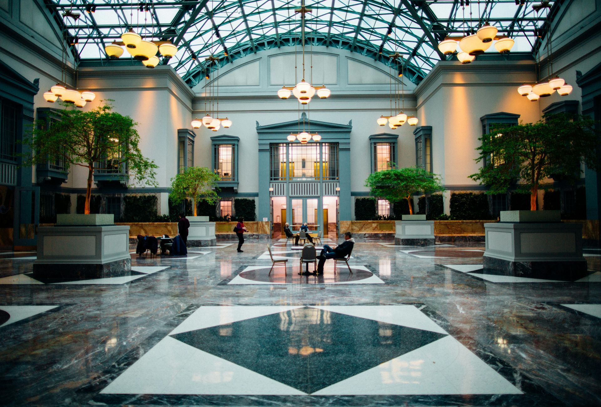 A group of people are sitting in a large lobby of a building.