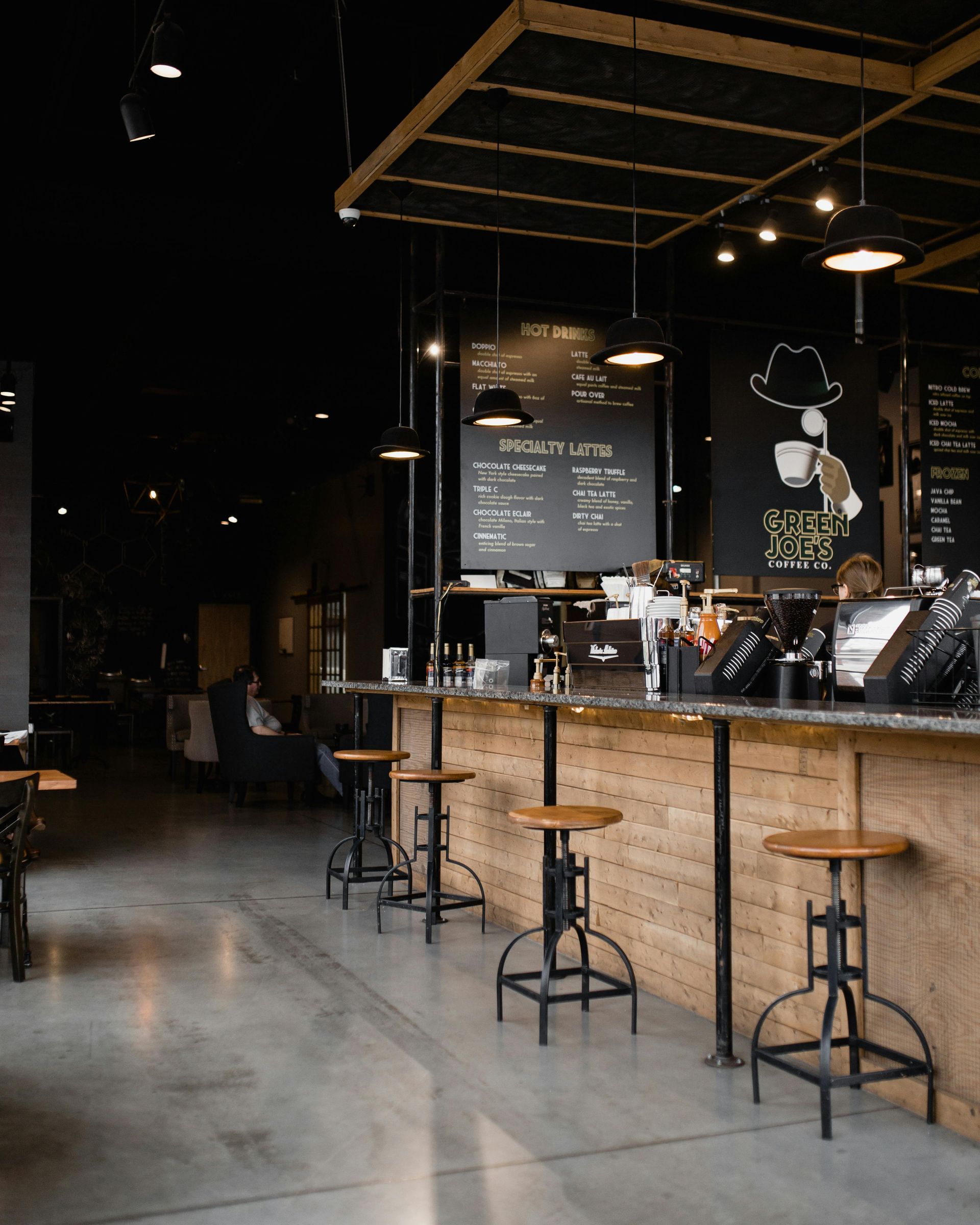 A restaurant with wooden tables and stools and a menu on the wall