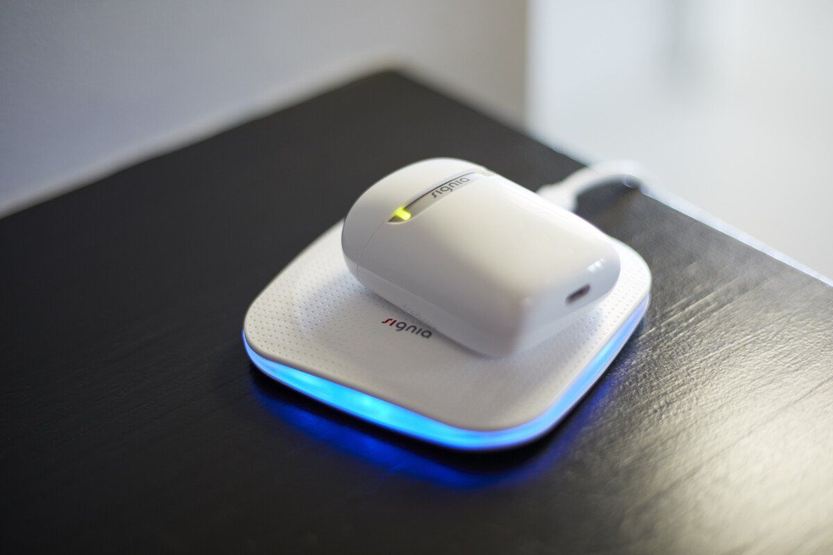 White wireless charger with a device on top, glowing blue and yellow lights.