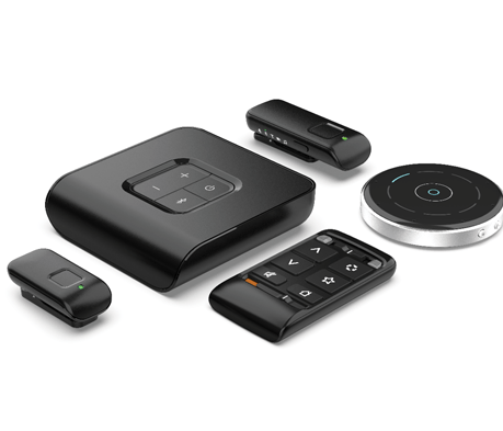 Various black remote controls and a central hub device, likely for home entertainment.